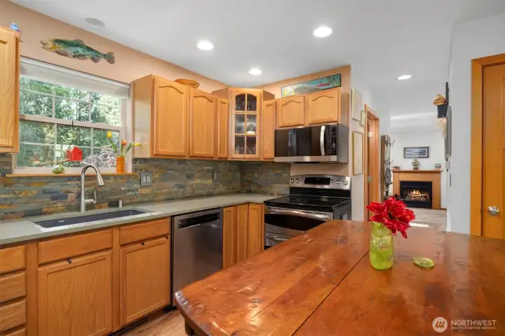 The kitchen looks to the forested rear property and there are a lot of quartz counters for food prep. The natural stone backsplash really pulls everything together. There are two separate ovens, and one is a convection oven.