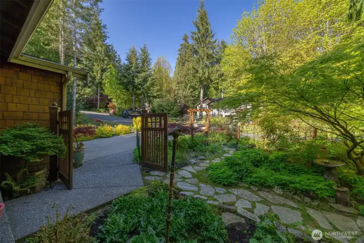 Looking from the front porch through the gate at the level parking area and all the flagstone pathways through the garden.