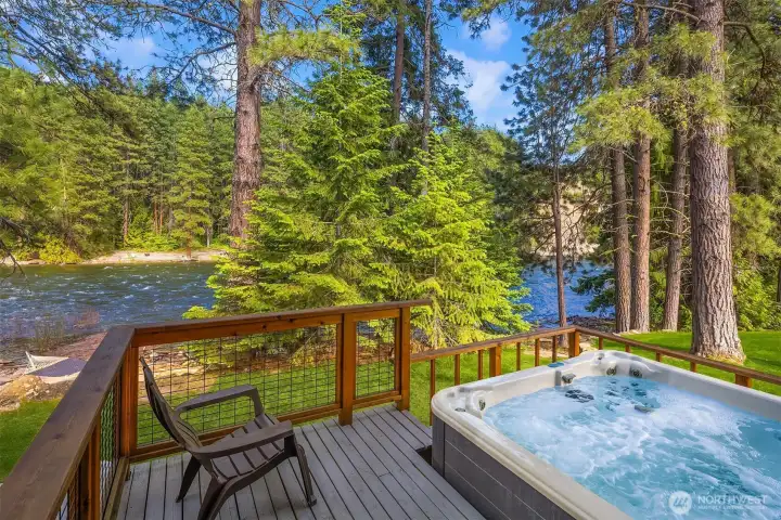 Private outdoor hot tub set on a wooded deck with tranquil views toward the Wenatchee River—perfect for relaxing after a day in the mountains.
