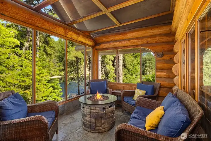 Inviting with cozy seating and fire table, surrounded by windows that showcase peaceful Wenatchee River views and forested privacy.