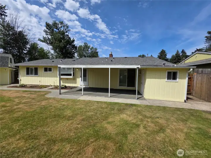 Back of house with covered patio and attached storage shed.