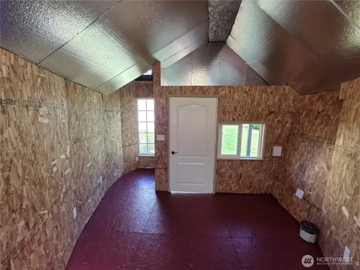 View towards the front of playhouse with door and windows and nook.