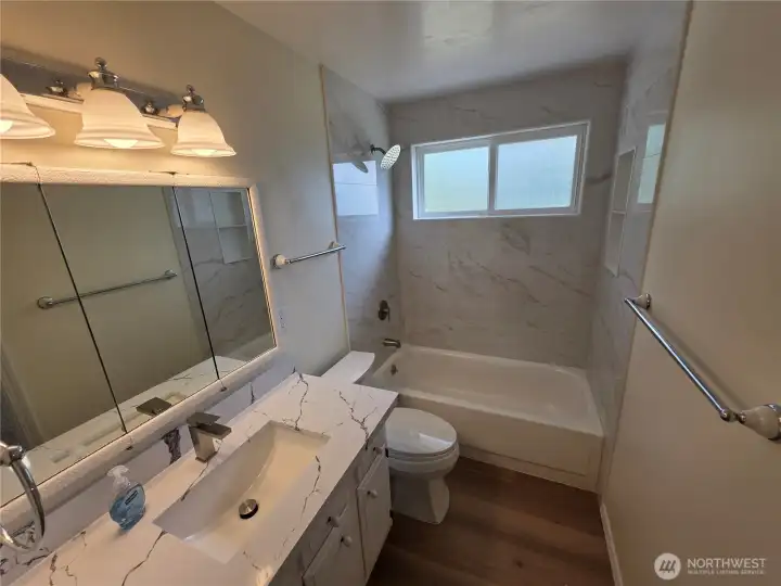 Remodeled bathroom with entrance to primary bedroom and hallway.