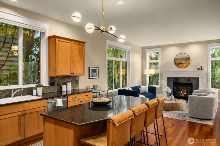 The open-concept kitchen is highlighted with designer lighting, stone counters, and wood cabinets. The open-concept kitchen is highlighted with designer lighting, stone counters, and wood cabinets.