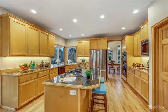 This kitchen is a chef’s dream, featuring expansive counter space, stainless steel appliances, and under-cabinet lighting. Large corner windows provide a view of the backyard, bringing in natural light to brighten the space.