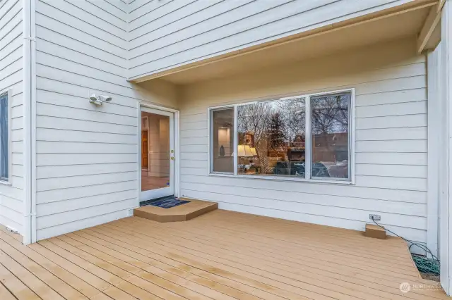 A closer look at the deck’s clean design, showcasing easy access to the interior living space through a glass door and a covered area for BBQing