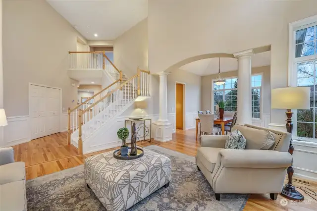 The seamless flow from the living room to the dining area makes entertaining effortless. Architectural details, such as decorative columns and wainscoting, add sophistication, while large windows bring in plenty of natural light.