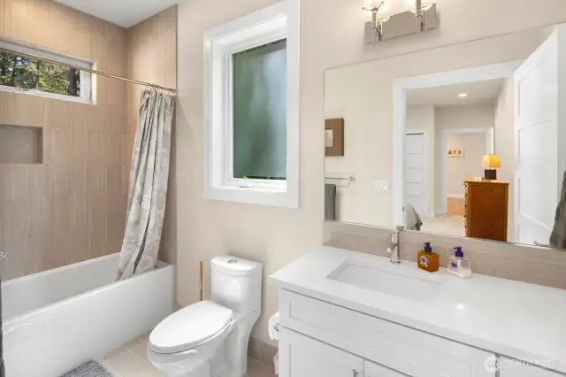 En-suite bath features a deep soaking tub and lovely tilework.