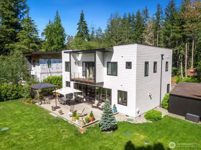 Another view of this wooded lot shows the large shed on the right side, and treehouse in the background. The siding and roof of the home are brand-new for added peace of mind.