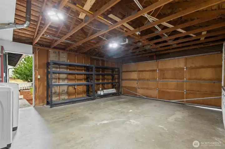 Two-car garage with open rafters, shelving and ample storage.