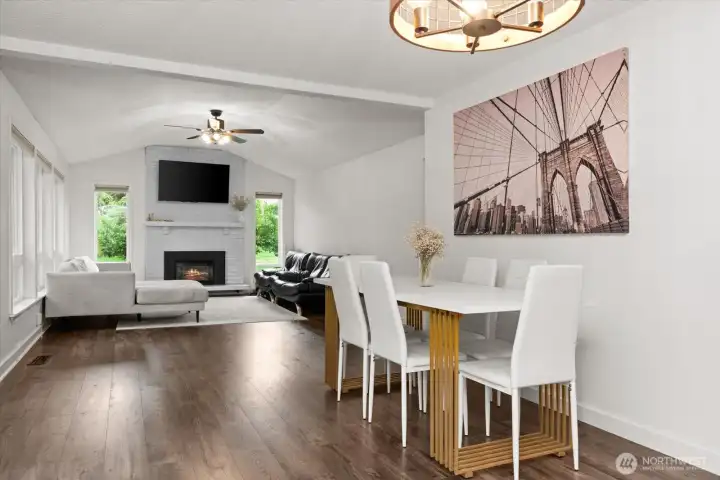 Dining area open to the living room with vaulted ceilings and fireplace.