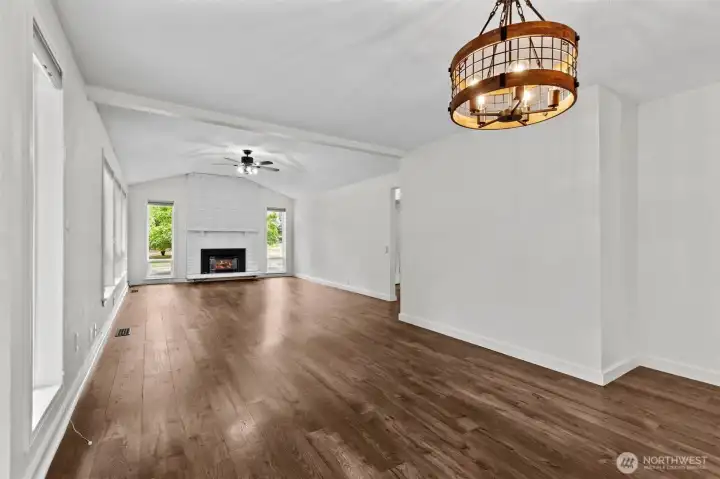 Bright living room with vaulted ceiling, fireplace, and tall windows.