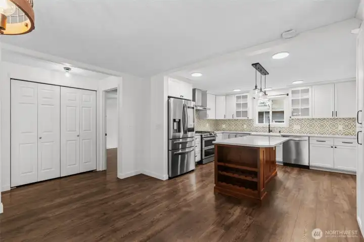 Modern kitchen with white cabinetry, quartz counters, and island with seating and storage.