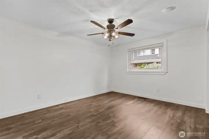 Spacious primary bedroom with ceiling fan and large window.
