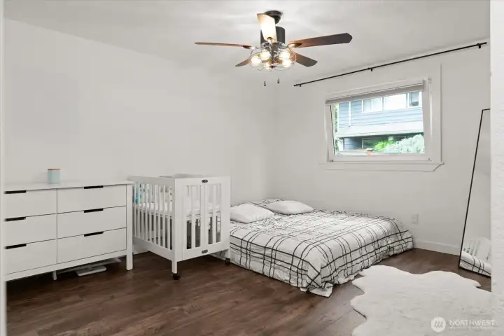 Spacious primary bedroom with ceiling fan and large window.