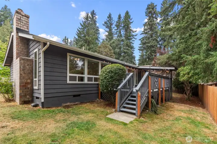 Back of home with steps up to the deck and fenced side yard.