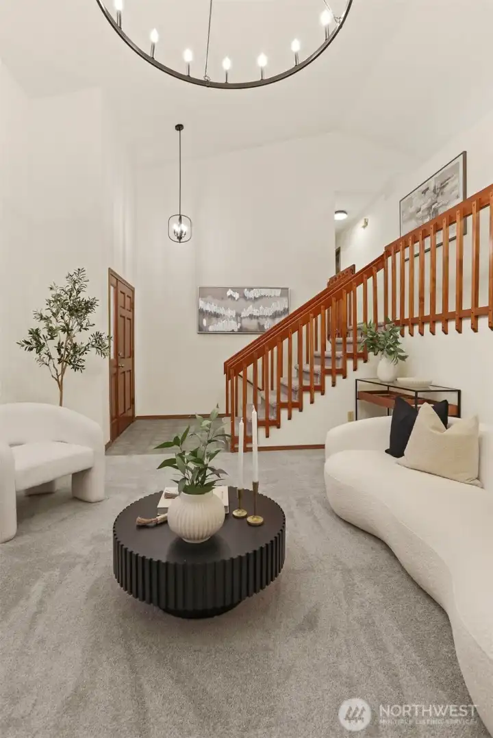 Living room looking to front entry and wide stair case to upper level.