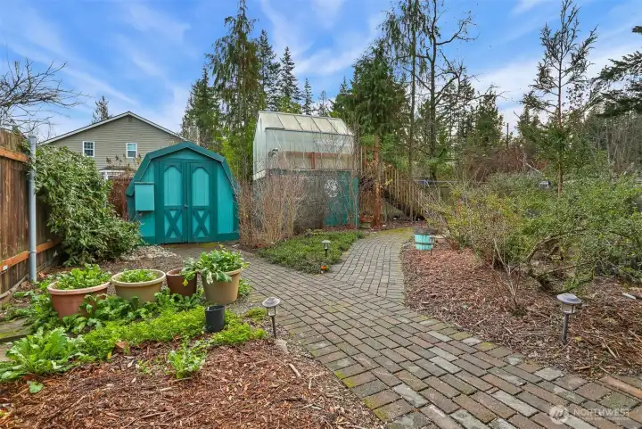 Private rear yard has garden shed, raised green house, paver walk ways around the native PNW gardens.