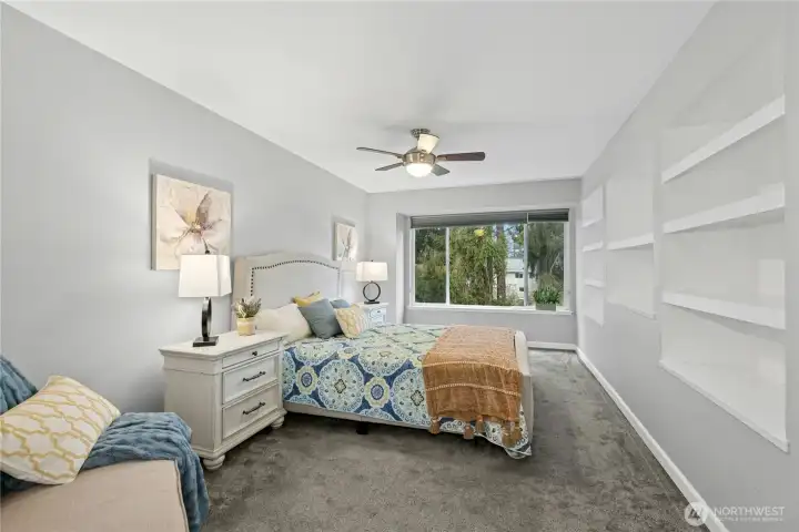 Oversized bedroom with built in shelves and large windows overlooking a peaceful wooded stream