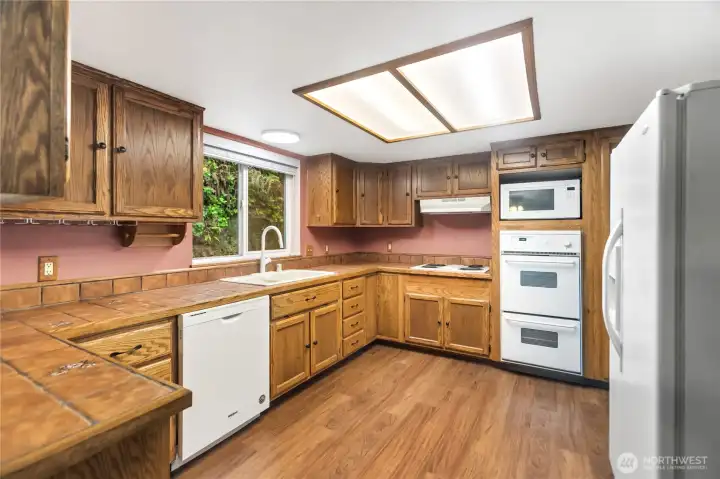 This large kitchen is a great place to cook with double ovens, plenty of counter and cabinet space and lots of light. Enjoy it in the current "time period" character or reimagine it to your liking (removal or reduction of the wall with the refrigerator and relocating the refrigerator would open the kithen to the views as well!). This large kitchen is a great place to cook with double ovens, plenty of counter and cabinet space and lots of light. Enjoy it in the current "time period" character or reimagine it to your liking (removal or reduction of the wall with the refrigerator and relocating the refrigerator would open the kithen to the views as well!).