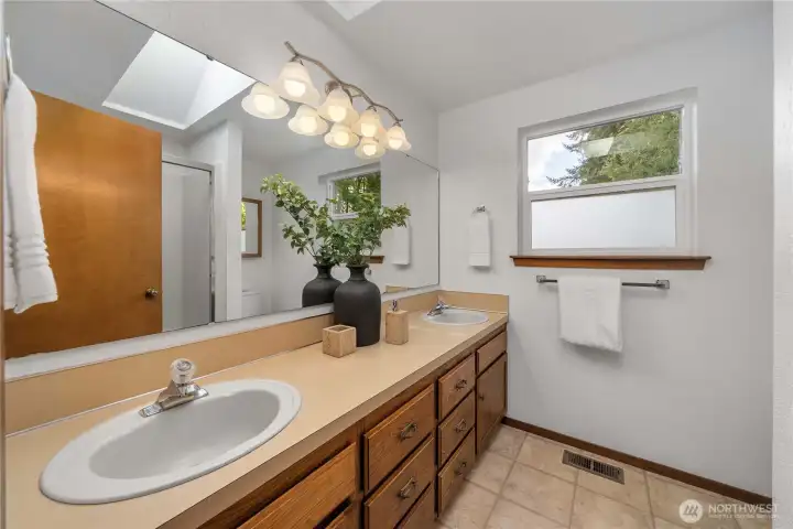 The primary bathroom features a dual-sink vanity and a skylight.
