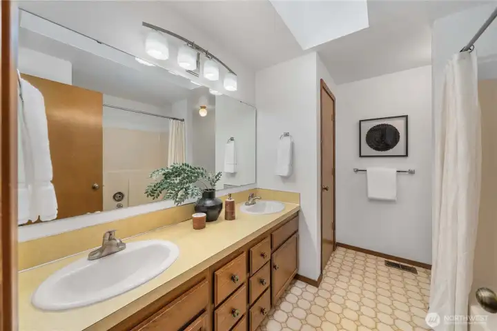 Large hall bath with linen closet, a tub-shower combo and a skylight.