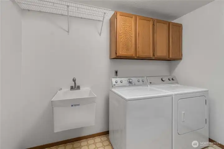 The spacious laundry room is appointed with a skylight, laundry sink, shelves, cabinets and the washer & dryer included