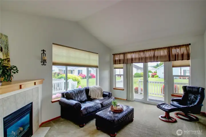 Light-filled living room with vaulted ceilings, gas fireplace, and seamless access to the covered back deck through sliding glass doors.
