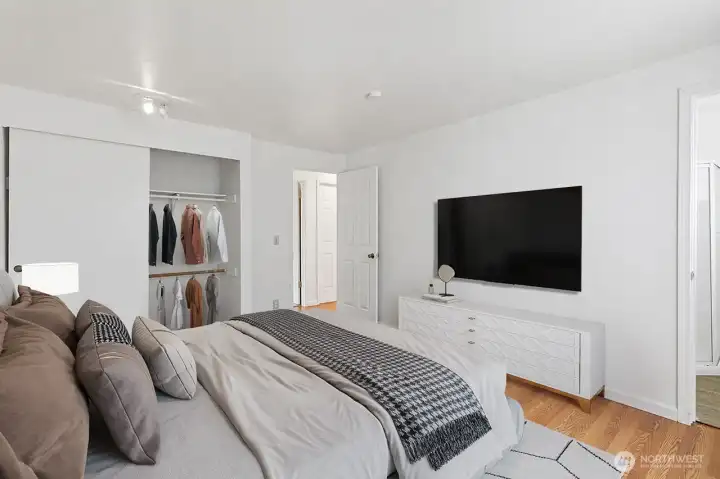 Virtually staged -A bright and spacious primary bedroom featuring warm wood floors, a nice closet and attached bathroom