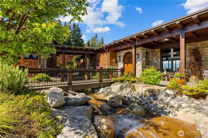 Incredible entry with National Park quality   water feature and bridge to front door.