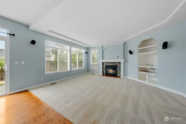 Family room with built in shelves, gas fireplace, carpet and large windows. Great room to make memories with friends and loved ones.