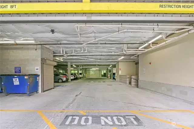 Parking garage includes garbage and recycling center, visitor parking, gated resident parking beyond, and secure lobby access on the right.