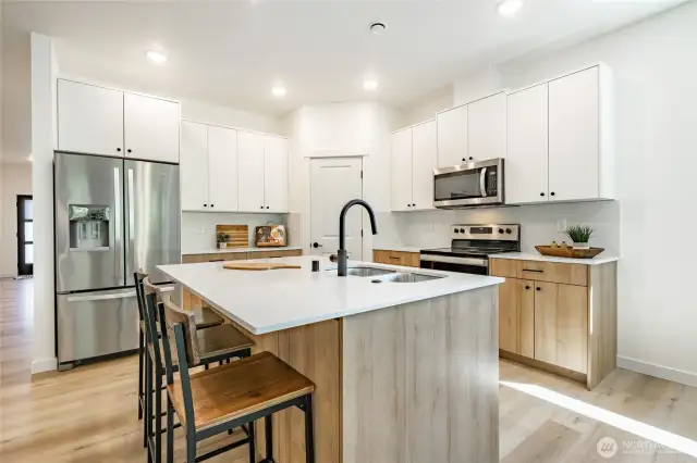 Quartz countertops with slab backspash. Photos shown are of a similar floor plan previously built in a different neighborhood (The Ridge in Blaine). Finishes and features may vary. Some items pictured reflect buyer-selected upgrades which are not included in the base price and may be added at an additional cost.