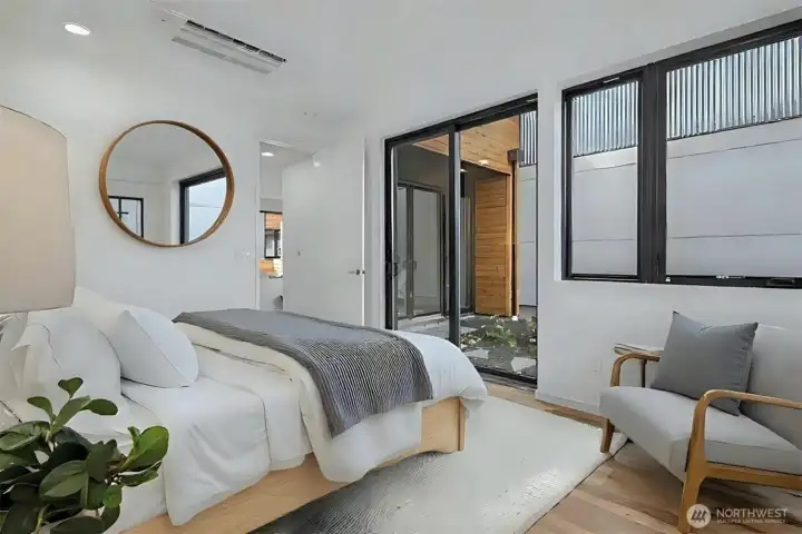 The main floor primary bedroom offers direct access to the private garden space through a large sliding glass door, creating a seamless connection between indoor comfort and outdoor tranquility.