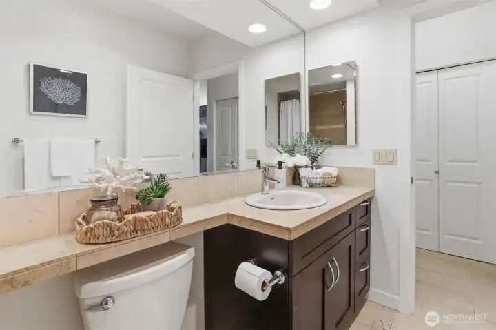 The bathroom has beautiful tile countertops, vanity storage space and an enormous mirror.