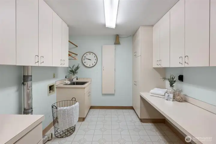 Large utility space with plenty of storage, built in ironing board, and utility sink.
