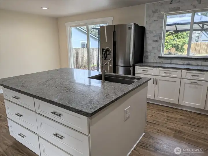 Updated & modernized kitchen with stone counter tops, large island, gas appliances, walk in pantry & pot filling faucet above the cookstove & new LVP flooring. #11823 150th St Ct E, Puyallup, WA 98374