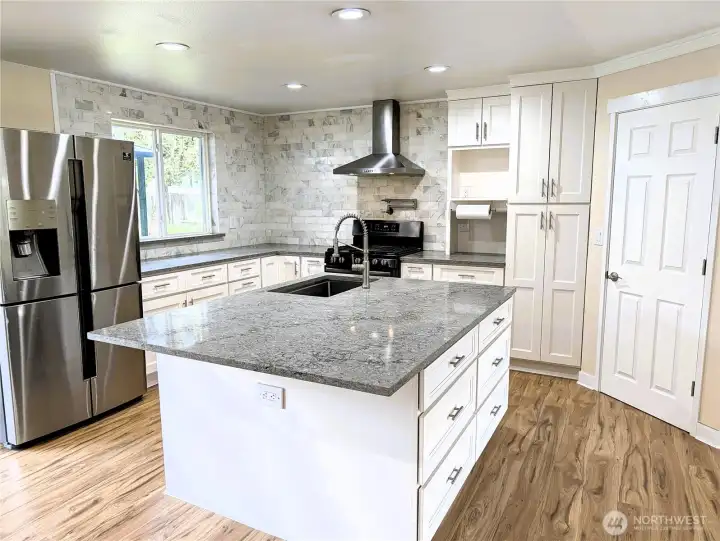 Updated & modernized kitchen with stone counter tops, large island, gas appliances, walk in pantry & pot filling faucet above the cookstove & new LVP flooring. #11823 150th St Ct E, Puyallup, WA 98374