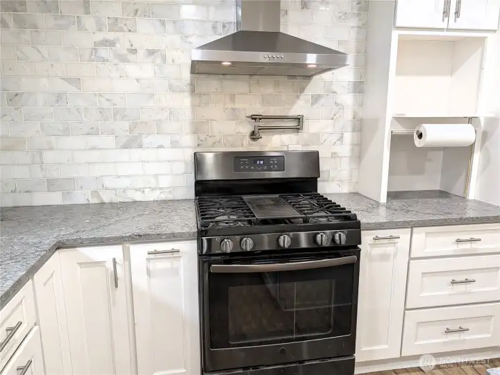 Updated & modernized kitchen with stone counter tops, large island, gas appliances, Walk in pantry & pot filling faucet above the cookstove. #11823 150th St Ct E, Puyallup, WA 98374