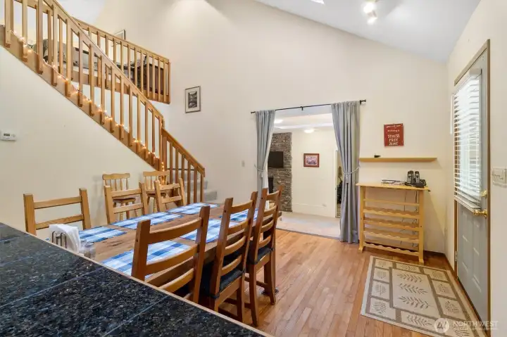 Dining area with hardwood floors, staircase to loft, and opening to living space.