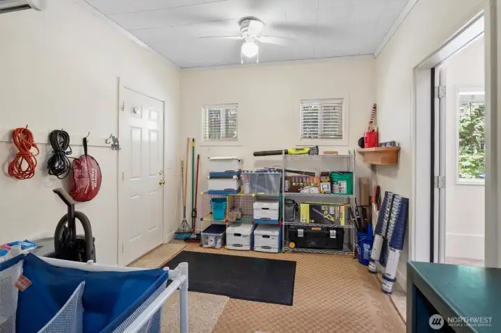 Mudroom or utility area with shelving, storage racks, windows, and exterior door.