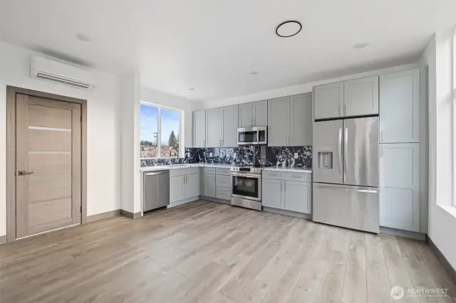 View of the kitchen from the dining room.  It showcases the lay out and high-quality finishes you can expect in the newly constructed home at 8608 & 8610 42nd Ave S, Seattle, WA 98118, built by the same builder.