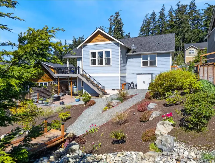 Back of home with expansive, low maintenance gardens