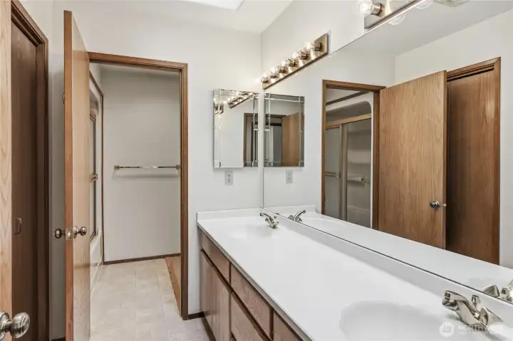 The bathroom on the main level has two sinks, large linen/storage closet, and skylights.  Just beyond the open door is a tub/shower combination.