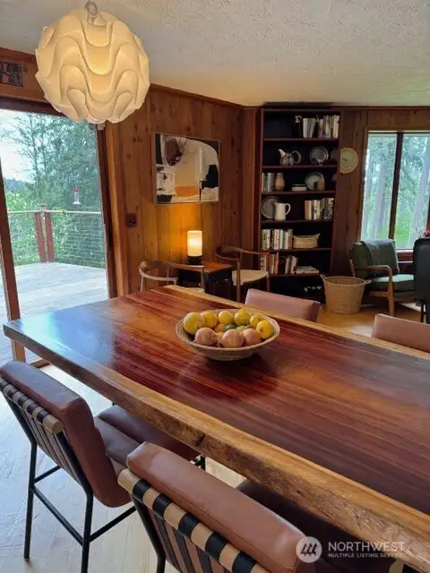 Dining area overlooks wood deck and trees.