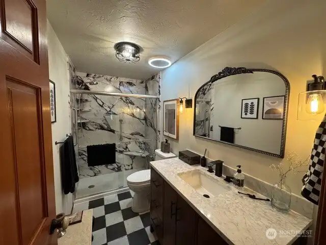 Hall bathroom newly remodeled with marble vanity, marble like stone shower and porcelain tile floors.
