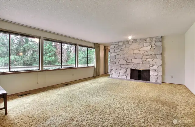 Formal living room with a two sided wood burning fireplace.  The wall of windows provide a view of the private back yard.