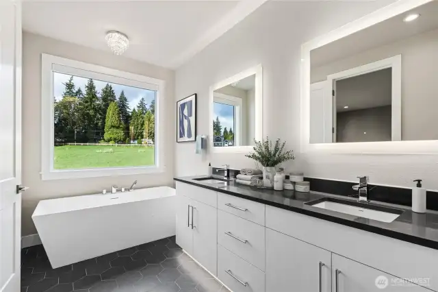 Primary suite features large soaking tub and dual guest vanity with slab quartz countertops. Photo of actual bathroom with virtual staging. View overlooking protected area/meadow.