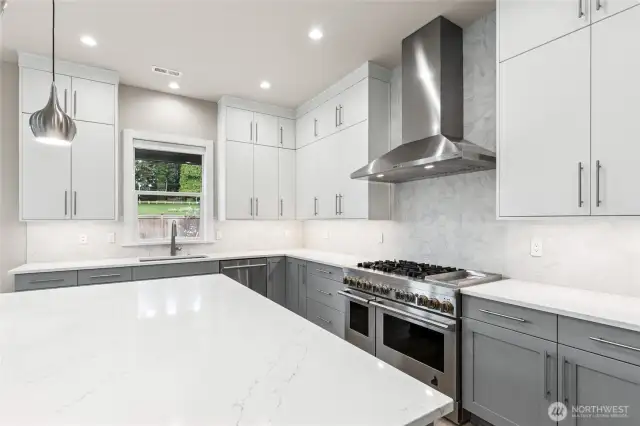 Kitchen features oversized slab quartz island. Stainless steel JennAir appliances and modern lighting!