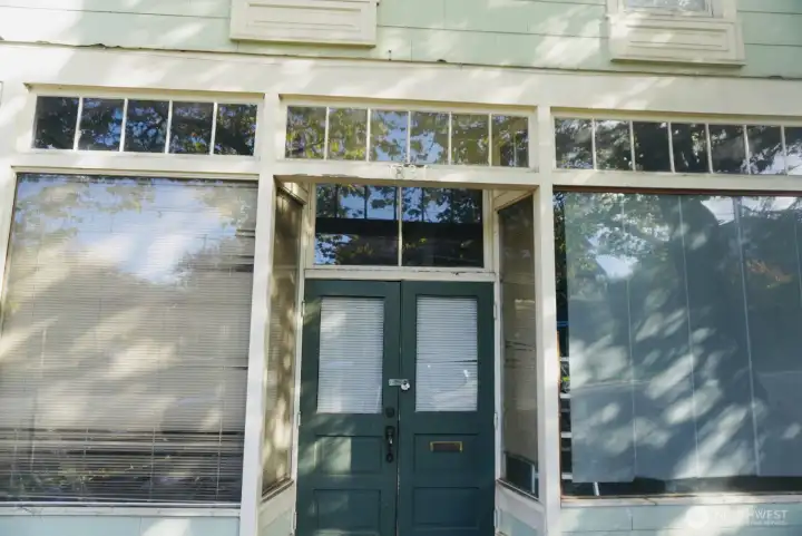 Charming double-door entry framed by transom and display windows—inviting natural light into the main level and showcasing the building’s classic character